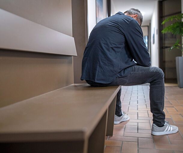 Ein Mann sitzt mit gesenktem Kopf auf einer Bank: Viele Betroffene, die in ihrer Partnerschaft häusliche Gewalt erleben, behalten die Schläge erst einmal für sich.